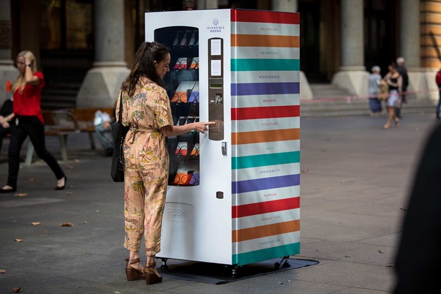 A person uses a brightly colored vending machine outdoors.