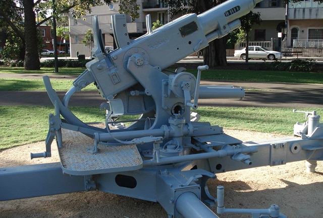 Artillery gun set on a circular cement base and is painted grey.