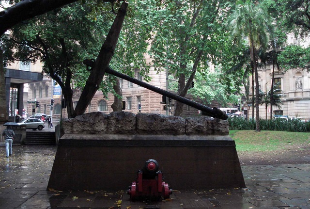 Large ships anchor on stone plinth with canon in front. 