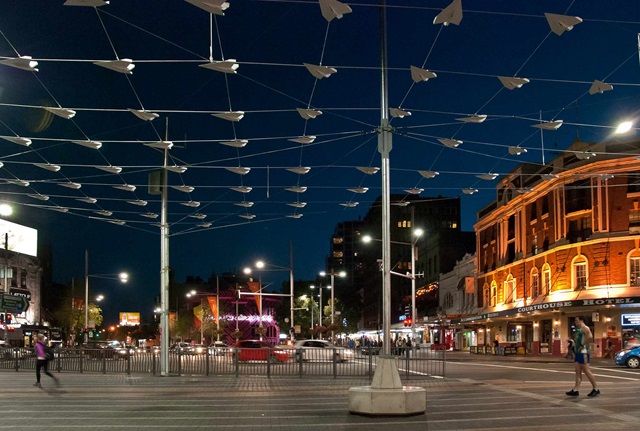 Installation of tiny paper aeroplanes cast shadows and movewhile suspended on wires above Taylor Square 