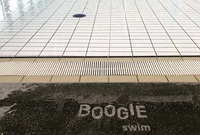 Splashed water on edge of a concrete swimming pool reveals words Boogie swim