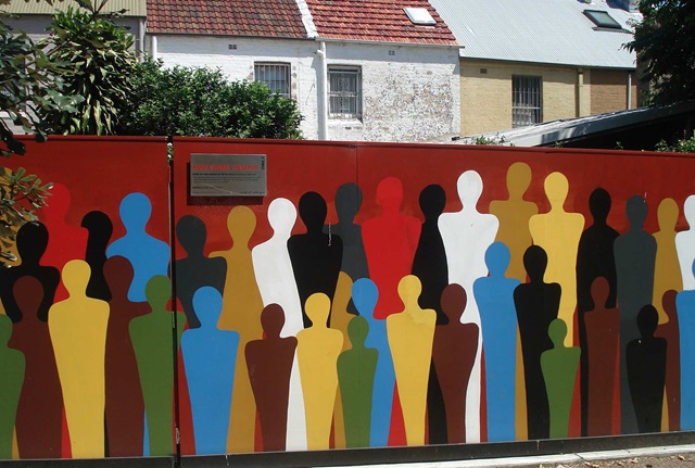 Brightly painted human like figures on a fence in a crowd formation