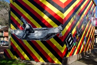 A red, black and yellow striped  mural covering an entire terrace house depicts Aboriginal leaders and vibrant graphic designs.