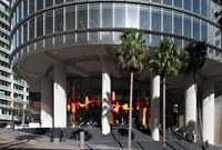 Large-scale aluminium sculpture, a complex network of ellipsoidal shapes painted in earthy tones sits within the entrance to an office building