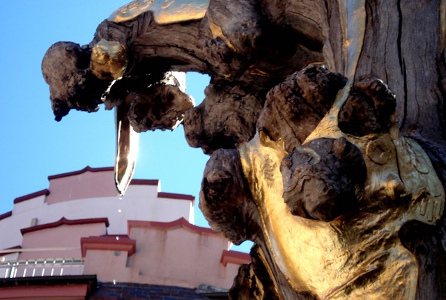 Close up of gold leaf  on a a sculpture made from the trunk of a tree.