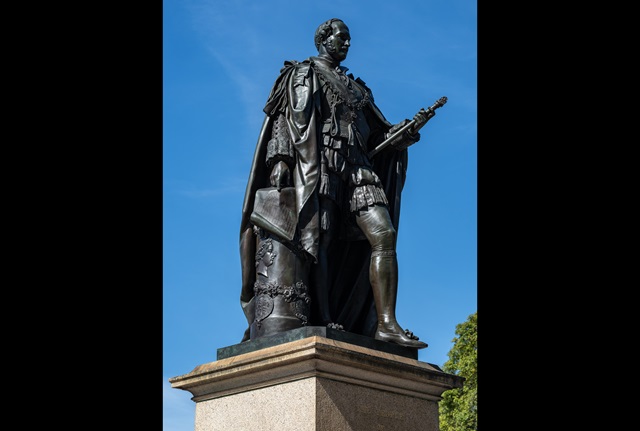 Larger than life bronze statue of Prince Albert in full regalia standing on a granite pedestal.