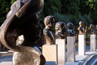 6 individual busts carved in alabaster each on top of a sandstone base and arranged in a arc at the top of small steps.