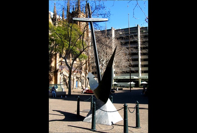 A very large bronze anchor mounted on a marble base.