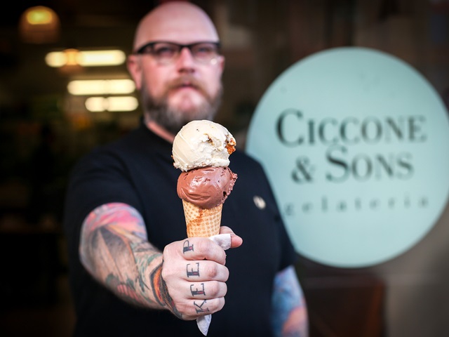 tattooed man holding ice cream cone outside a shop
