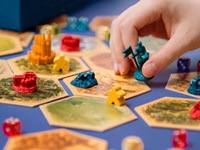 Close up of a person moving a piece  while playing a colourful boarad game