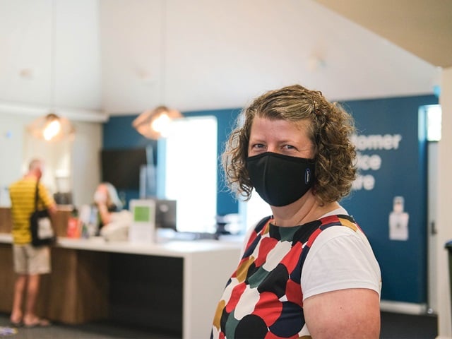 Team member at Glebe library wears face mask and a customer service employee helps customer in the background.