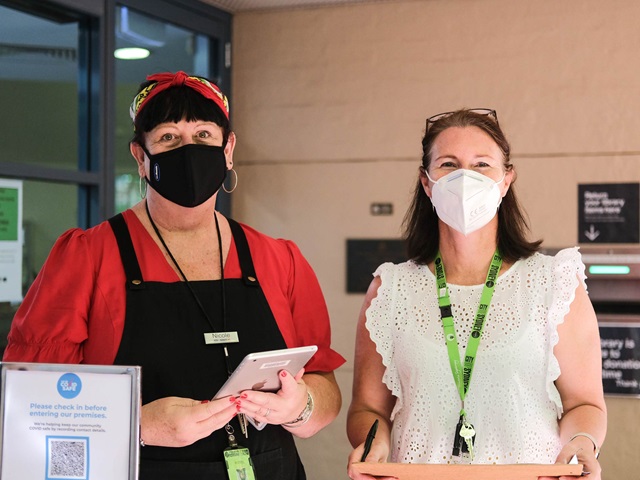 2 staff members wearing masks and using covid QR code check in system