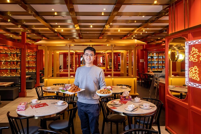 An entrepreneur holding plates of food in a restaurant in Haymarket.