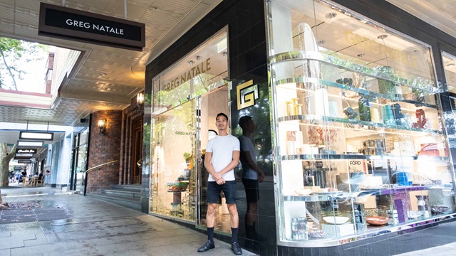 Man in shorts and T shirt standing outside of Greg Natalie storefront