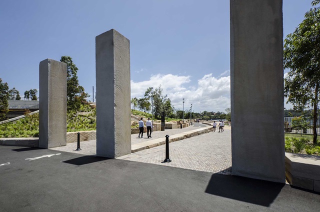 People walking along a path way with tall concrete arches in the foreground.