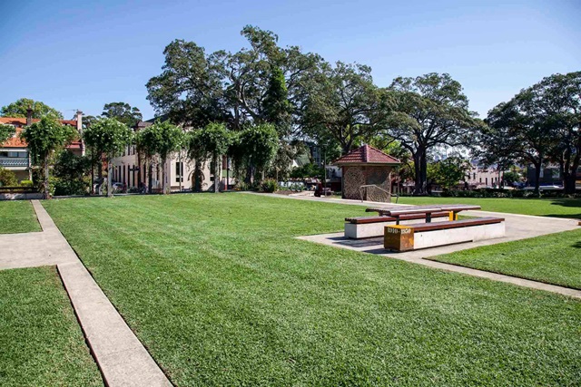 Wide open grassed area with a table and benches to sit.  