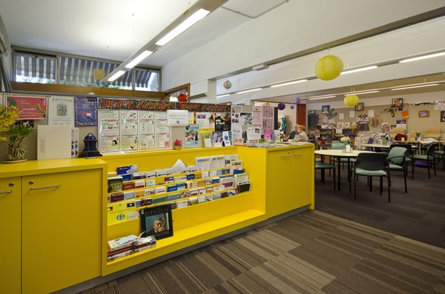 A yellow bookshelf filled with resources in Cliff Noble Community Centre.