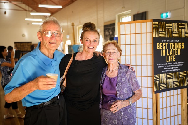 Three people embraced and smiling at the camera.