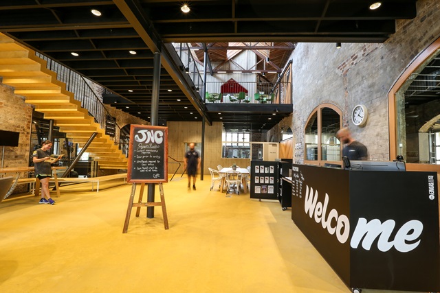 A room with a welcome sign on the left, a free standing small chalkboard in front and stairs in the background.
