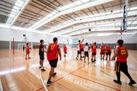 Teens playing basketball in a large indoor court.