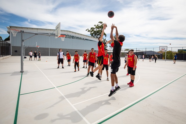 Teen playing basketball in an outdoor court.