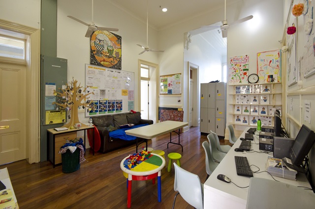 A room with computers, a sofa and a kid's table.