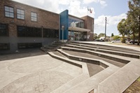 An area in the front that resembles an amphitheatre set-up and a big building in the background.