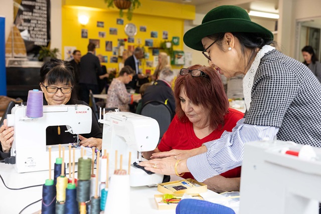 Three people working on sewing machines at a table