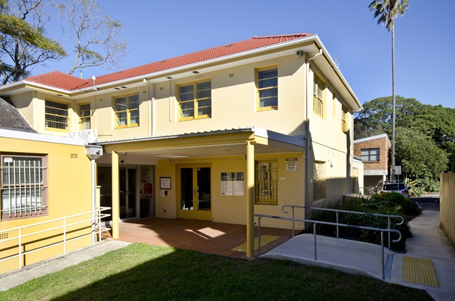 A 2 storey big building with grass out the front.