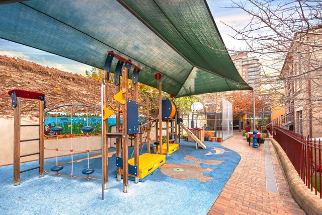 Children's playground under a shaded sail.