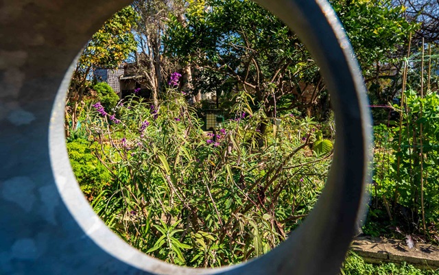View of a community garden through the centre of a stone sculpture