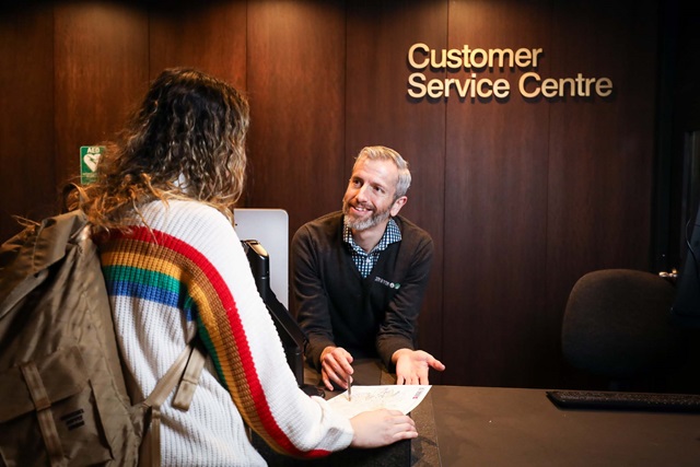 A customer service agent talks to a person over a desk.
