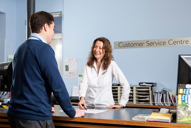 A customer service officer helps a customer at the front desk.