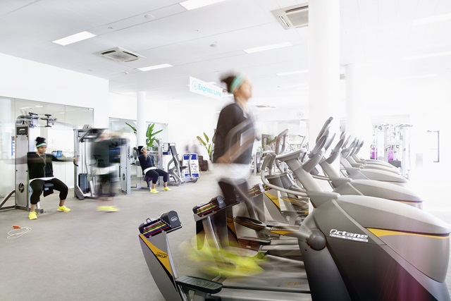 A woman using the cardio and weights machines in the gym.