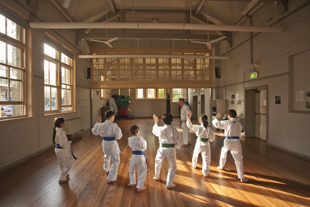 A group of children wearing karate clothing doing karate.