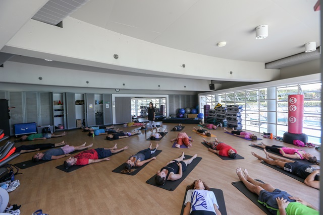 People lying on yoga mats in a large room.
