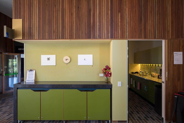 A bench with cupboards below and to the right inside a small room is a small kitchenette.