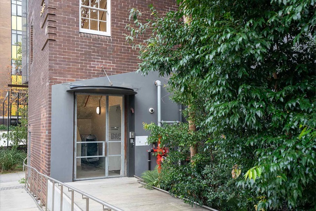 Ground floor entry to a brick building with automatic door and concrete ramp