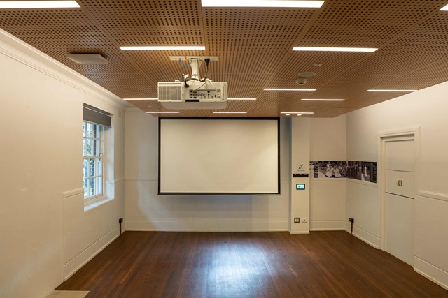 An modern empty meeting room with a wooden floor, projector and screen