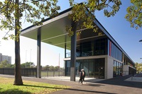 The front of a modern building surrounded by trees with large window.