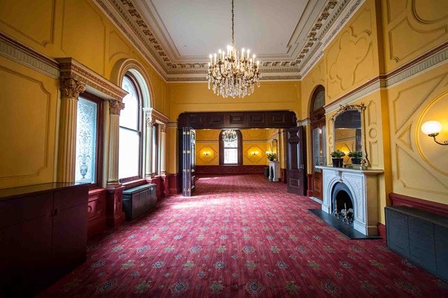 Red-carpeted heritage room with chandelier.