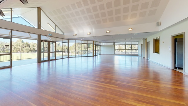 a large empty room with wooden floors, surrounded by lots of windows and an open door leading to a balcony