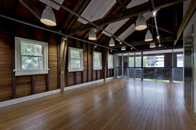 A large hall with wooden floors, lighting and large windows.