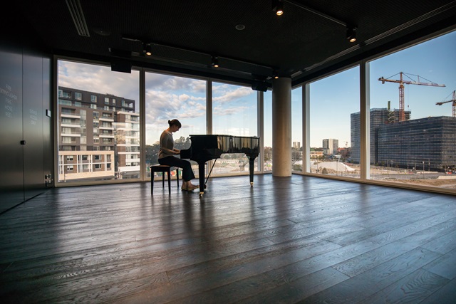 Lady playing baby grand piano in music room Green Square Library