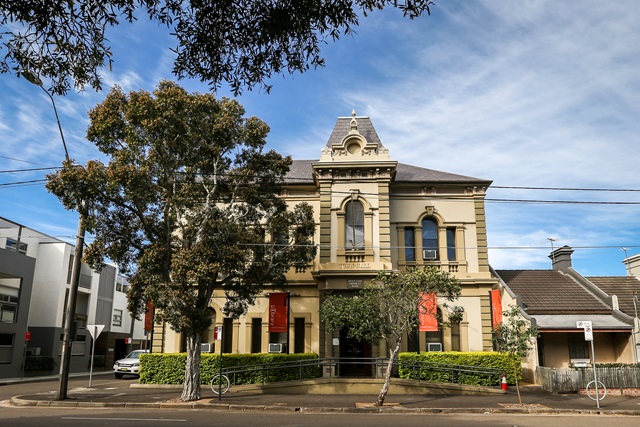 Street view with a large tree and 2 storey historic building.