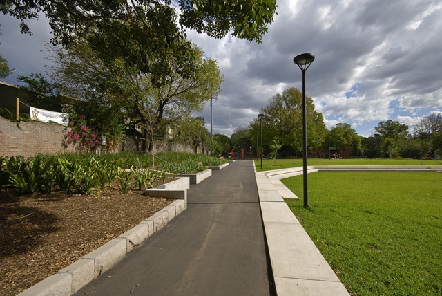 A walking path with garden beds on the left and grass on the right