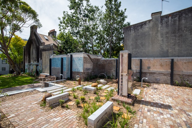 Outdoor garden with benches, large trees and old bricks used to pave walkways.