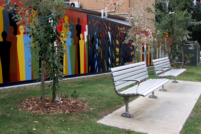 A vew of park benches and the new Indigenous art work 'Wall of Humanity' designed by artists Bronwyn Bancroft and Dales Jones-Evans, and painted by local children, Hugo Street Reserve.