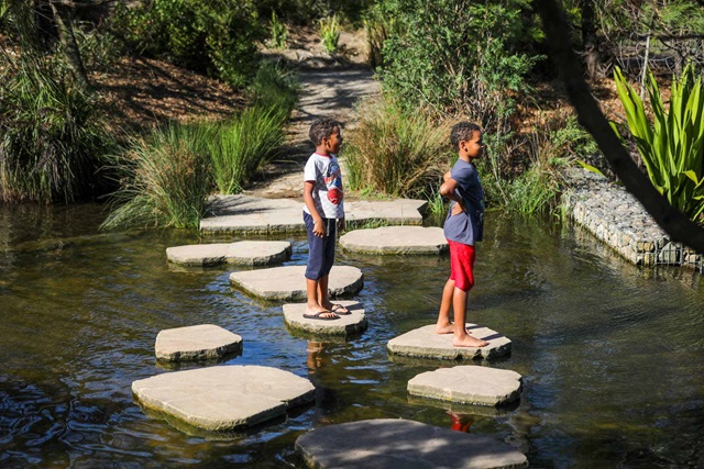 Two children play on stepping stones in the water