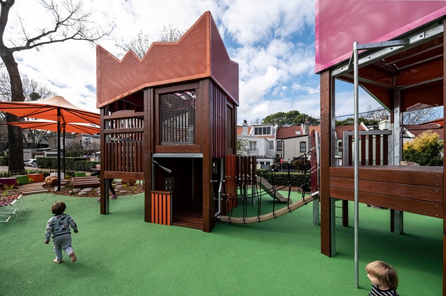 A playground with a rope bridge and a couple of people.